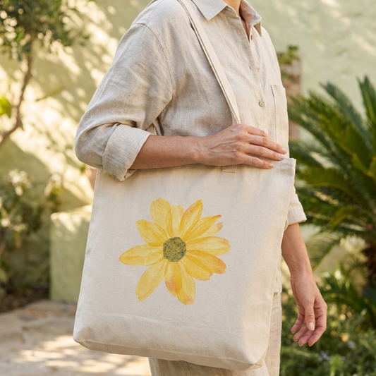 Person holding a tote bag with a sunflower design outdoors.